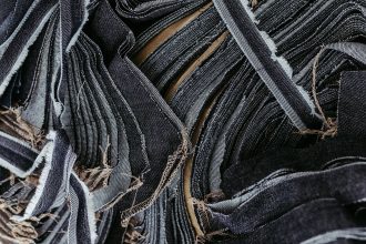 Close-up de tiras sobrepostas de tecido jeans em diferentes tons de azul, destacando suas texturas.