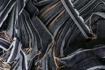 Close-up de tiras sobrepostas de tecido jeans em diferentes tons de azul, destacando suas texturas.