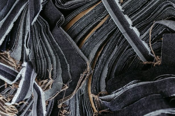 Close-up de tiras sobrepostas de tecido jeans em diferentes tons de azul, destacando suas texturas.