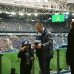 Torcedores acompanham uma partida de futebol nas arquibancadas de um estádio.