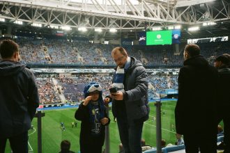 Torcedores acompanham uma partida de futebol nas arquibancadas de um estádio.